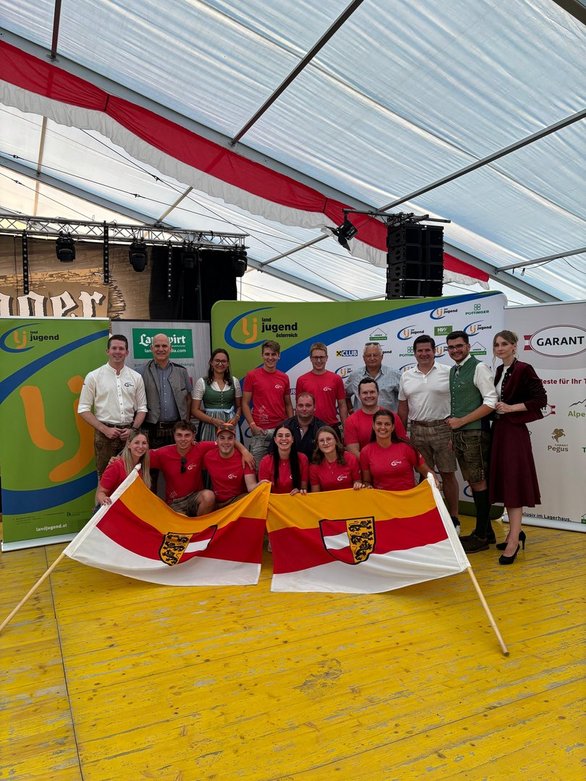 Landjugend-Teilnehmer mit Kärntner Fahnen vor Sponsoren-Banner